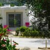 Casa bianca con giardino e piante fiorite.