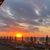 Tramonto su una spiaggia con ombrelloni chiusi.
