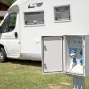 Un camper parcheggiato accanto a una colonnina elettrica aperta.
