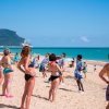 Persone fanno ginnastica sulla spiaggia, in costume da bagno.