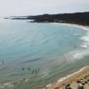 Spiaggia con ombrelloni e bagnanti in mare.