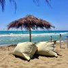 Spiaggia con ombrellone di paglia e cuscini.