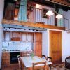 Cucina in legno con soppalco sopra, tavolo e sedie, e dettagli di travi a vista.