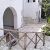 Ingresso con arco e vialetto in pietra, affiancato da piante.
