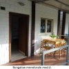 Veranda di bungalow con tavolo e sedie all'aperto.