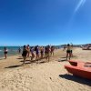 Persone ballano su una spiaggia assolata.