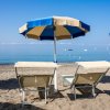 Due lettini e ombrellone blu sulla spiaggia.