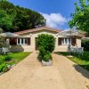 Casetta gialla con giardino fiorito e ombrelloni.
