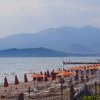 Spiaggia con ombrelloni arancioni e montagne in lontananza.