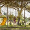 Bambini giocano su struttura sospesa con scivolo.