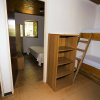 Stanza con letto a castello, libreria vuota e porta aperta verso un’altra camera con letto.