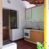 Cucina all'aperto con forno, fornelli, lavello e armadietto, vicino a una porta finestra.