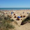 Spiaggia affollata con ombrelloni e mare calmo.