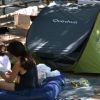 Due persone leggono su un materasso accanto a una tenda verde.