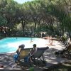 Persone sedute su sdraio accanto a una piscina circondata da alberi.