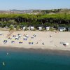 Spiaggia con ombrelloni e sdraio, mare calmo.