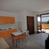 Cucina moderna arancione, tavolo e sedie, porta aperta su terrazza con vista.