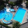 Vista dall'alto di due piscine, uno scivolo e lettini intorno.