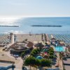 Vista aerea di una spiaggia attrezzata e piscina vicino al mare.