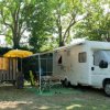 Camper parcheggiato all'aperto con ombrellone e sedie.