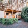 Bungalow in legno con veranda circondato da alberi.