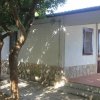 Bungalow bianco con porta in legno, ombreggiato da alberi.