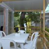 Terrazza con tavolo bianco e sedie, vista su un giardino.