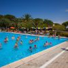 Lezione di acquagym in piscina con istruttore sulla riva.