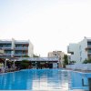 Piscina all'aperto circondata da edifici moderni e persone sedute ai tavolini.