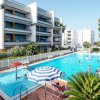 Piscina all'aperto con ombrelloni e palazzi bianchi.