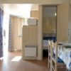 Interno di una casa vacanze con tavolo apparecchiato, sedie e tende a fiori.