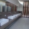 Bagno pubblico elegante con lavandini in fila e divisori.