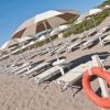 Spiaggia con lettini, ombrelloni e un salvagente arancione.