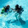 Due subacquei in piscina, in tenuta completa con bombole e maschere.