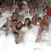 Un gruppo di persone si diverte in una festa di schiuma all'aperto.