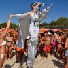 Una persona su trampoli in abito argentato sulla spiaggia.