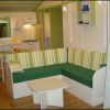Un soggiorno con divano ad angolo verde, cucina sullo sfondo e tavolino bianco.